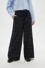 Pantalon de corte ancho y tiro alto, confeccionado en tela con estampado de cuadros oscuros. Cuenta con cintura elástica con cordón de ajuste y bolsillos laterales.