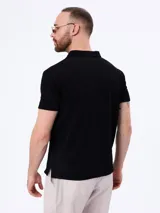 Remera polo de manga corta en tejido cloqué color gris, con cuello camisero y cierre frontal de botones.