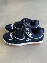 Championes DC modelo Kalynx Zero, color azul marino con detalles en blanco y suela de goma color caramelo. Confeccionados en malla y gamuza, con cordones azules y logo de la marca en el lateral y la lengüeta.