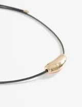 Collar de cordón negro con dije metálico de forma curva y acabado plateado.