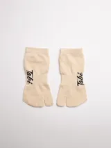 Par de medias color beige con separación para el dedo gordo, con logo 'Tabi' en el lateral.