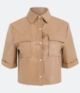 Camisa de manga corta confeccionada en cuero sintético color tostado, con cuello camisero, cierre frontal con botones en forma de corazón y dos bolsillos con solapa en el pecho.