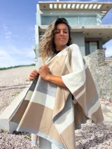 Ruana tejida con diseño de franjas horizontales en tonos beige, gris y crudo, de corte abierto y caída fluida.