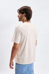 Remera de manga corta en color gris claro, con cuello redondo y estampa pequeña en el pecho con texto alusivo.