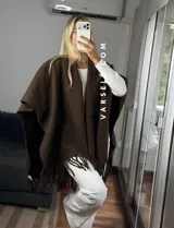 Poncho de tejido suave color blanco, con diseño abierto y flecos en el ruedo inferior.