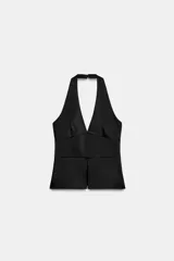 Top halter satinado de color negro, con escote en V profundo, espalda descubierta, bajo en evasé con abertura frontal y cierre lateral con cremallera oculta.