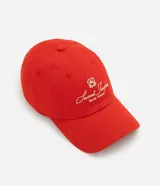 Gorra roja confeccionada en sarga de algodón, con visera curva y bordado frontal en tono claro con la inscripción "Saint Tropez South France" y un escudo. Cuenta con ojalillos de ventilación y ajuste posterior.