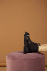Botas tipo Chelsea con paneles elásticos laterales, confeccionadas en una combinación de cuero liso y gamuza en tonos marrones. Presentan una suela track robusta y dentada en color beige.