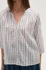 Camisa de algodón con diseño de rayas verticales y detalles bordados. Presenta cuello en V, cierre frontal con botones y mangas tres cuartos con terminación elástica.