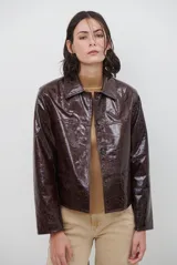 Chaqueta de efecto cuero brillante con acabado charol, cuello con solapas de piel sintética, cierre frontal con botones y bolsillos laterales.
