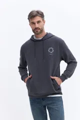 Canguro con capucha y cordones ajustables, confeccionado en algodón color gris oscuro. Presenta un diseño de estampa circular sutil en el pecho y bolsillos laterales.