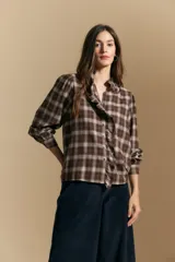 Camisa de algodón a cuadros con diseño de volados frontales, cuello alto y mangas largas con leve volumen.