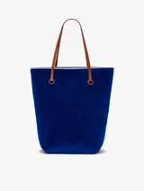 Bolso tipo tote de chenilla color verde oscuro con ribete amarillo. Tiene dos correas de hombro color crema, compartimento principal con bolsillos internos y apliques metálicos con el logo de la marca.