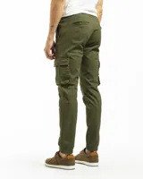 Pantalón cargo estilo jogger color verde oliva, confeccionado en algodón con spandex. Presenta cintura con elástico y pasadores para cinturón, cierre frontal y puños ajustados en los tobillos. Cuenta con múltiples bolsillos cargo laterales.