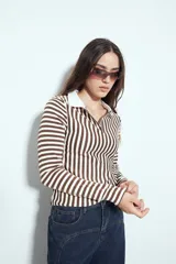 Remera de manga larga a rayas verticales verdes y blancas, con cuello polo y cierre frontal de botones. Presenta un diseño ajustado al cuerpo.