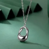 Collar de acero quirúrgico plateado, con cadena fina de eslabones y dije orgánico de diseño irregular.