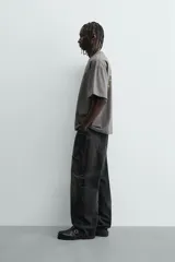 Camiseta de manga corta y cuello redondo, color gris oscuro con efecto lavado. Presenta un pequeño estampado en el pecho con texto en color verde lima.