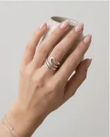 Anillo de acero plateado con diseño abierto en forma de espiral o bucles entrelazados.