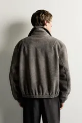 Cazadora de hombre regular fit confeccionada en tejido efecto ante, con acabado lavado, cuello solapa, manga larga, bolsillos de plastrón con solapa en la cadera, detalles elásticos en puños y cintura, y cierre frontal de cremallera.