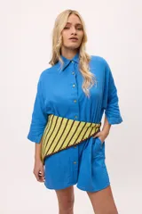 Vestido camisero negro de algodón, con mangas tres cuartos y cuello camisero. Presenta detalles de costura en zigzag color naranja en el cuello y en los puños.