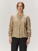 Camisa de lino liviano color tostado, con silueta relajada, cuello mao, alforzas verticales frontales, mangas con volumen y puños elastizados con volados.
