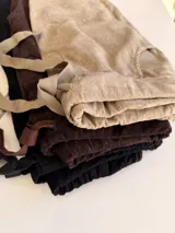 Pantalón de corte relajado color beige, con cintura elástica y cordón ajustable. Presenta parches decorativos con lentejuelas y tachas en los muslos, además de detalles de texto estampado. Posee bolsillos laterales y dobladillo en los tobillos.