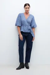Blusa cruzada celeste con estampado floral, mangas cortas abullonadas y lazo en la cintura.