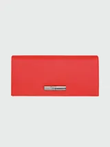 Billetera continental Longchamp modelo Le Roseau, confeccionada en cuero con textura granulada, color rojo. Presenta un cierre frontal con el icónico broche metálico de bambú de la marca.