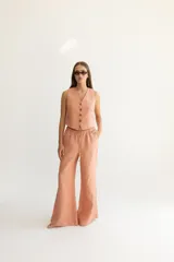 Pantalón color beige de lino, con elástico y tira ajustable en la cintura, bolsillos a ambos lados y pata de elefante estilo Oxford.