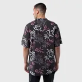 Camisa de manga corta con cuello cubano, confeccionada en viscosa con estampado botánico de hojas en tonos grises, blancos y violetas sobre fondo negro.
