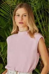 Blusa color rosa pálido sin mangas, con cuello alto y lazo decorativo.