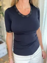 Camiseta negra de microfibra con cuello redondo y mangas cortas, con detalle de encaje en el escote y en los puños.