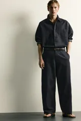 Pantalón chino para hombre confeccionado en denim ligero de mezcla de algodón y lino, sin lavados. Presenta un corte relajado con tiro medio, bolsillos frontales, bolsillos traseros y cierre frontal con cremallera y botón.