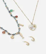 Conjunto de bisutería compuesto por dos collares y un par de aros tipo argolla. Un collar presenta una cadena dorada con un dije de corazón que contiene flores secas encapsuladas, mientras que el otro collar combina una cadena trenzada multicolor con diversos dijes colgantes, incluyendo tréboles, una mariquita, la palabra 'LOVE' y un pez. Los aros son argollas pequeñas doradas con detalles grabados.