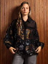 Camisa de manga larga con diseño de terciopelo estampado con motivos florales y paisley, combinada con paneles de tela transparente en la parte superior. Presenta cuello clásico, cierre frontal con botones y mangas abullonadas.