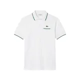 Chomba Lacoste modelo L12.12 color blanco, de manga corta, con cuello polo y ribetes verdes en cuello y mangas. Cuenta con un bolsillo frontal en el pecho con ribete verde y el logotipo del cocodrilo bordado sobre este.