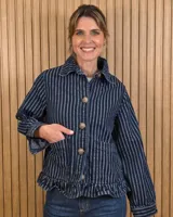 Sobrecamisa de pana suave a rayas con solapa, cierre frontal de botones, bolsillos aplicados y detalle de volado en el ruedo.