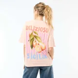 Camiseta oversize de color rosado con cuello redondo y mangas cortas. En la espalda presenta un estampado gráfico que incluye la leyenda "DELIZIOSO SICILIA", rayas verticales y frutas cítricas con hojas.