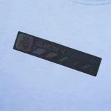 Remera celeste con cuello redondo y estampado rectangular negro con el logo del Real Madrid en el pecho.