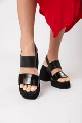 Sandalias negras de cuero con plataforma delantera de 3 cm y taco de 9 cm forrado. Tiene doble tira y ajuste con hebilla.