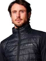 Chaqueta híbrida para hombre con cuerpo acolchado y mangas de tejido softshell liso. Presenta cierre frontal completo, cuello alto y logo de la marca estampado en el pecho. Diseñada con tecnología repelente al agua y aislamiento térmico sintético.