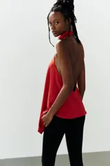 Top halter asimétrico de color rojo, confeccionado en tejido elástico, con cuello alto y cierre posterior con botones.