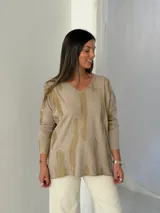 Sweater de punto color visón con estampado abstracto en color dorado brillante, cuello en V y mangas largas con diseño holgado.