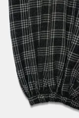 Pantalón bombacho de tiro medio con estampado a cuadros en tonos oscuros (negro, gris, blanco). Presenta cintura elástica ajustable con cordones y bajo abullonado con elástico.