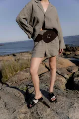 Sandalias planas con punta cuadrada, base negra y capellada de cuero marrón con textura trenzada.