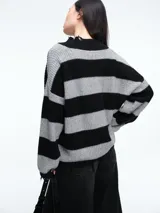 Sweater de tejido de punto con diseño a rayas horizontales en negro y gris. Presenta cuello en V con terminaciones desflecadas, corte holgado y mangas largas con puños desflecados.