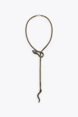 Collar tipo lariat con cadena de malla metálica color bronce envejecido. El diseño presenta una serpiente con cabeza y cola incrustadas con pequeños brillos oscuros, anudada en el centro.