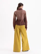Pantalón de corte ancho y silueta relajada, confeccionado en tejido técnico con elasticidad. Presenta recortes verticales en el frente que terminan en aberturas en el ruedo y cuenta con un cinturón integrado con hebilla metálica de enganche.