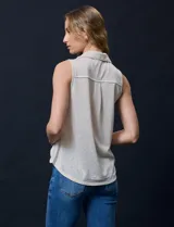 Blusa color crema sin mangas, con cuello camisero, cierre frontal con botones y bolsillo de crochet.