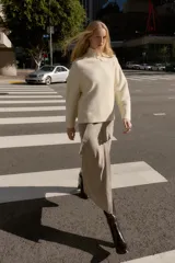 Jersey de punto liso color beige, con cuello subido y manga larga. Presenta acabados en rib en cuello, puños y ruedo.